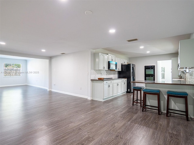 1735 18th St, Vero Beach, FL 32960 - kitchen with stainless steel microwave, refrigerator with ice dispenser, a sink, dark wood-type flooring, and a kitchen bar