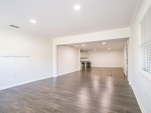 unfurnished living room with visible vents, baseboards, dark wood finished floors, and ornamental molding