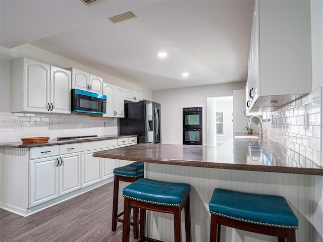 kitchen with dark countertops, visible vents, stainless steel refrigerator with ice dispenser, and dobule oven black