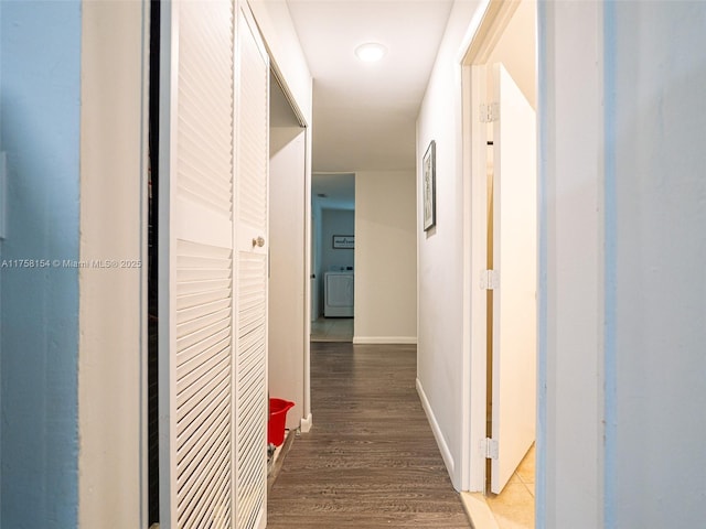 hallway featuring baseboards, washer / clothes dryer, and wood finished floors