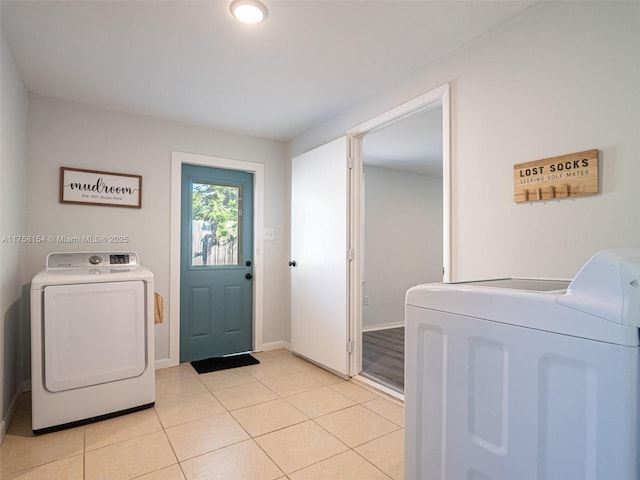 laundry room with baseboards, light tile patterned flooring, washing machine and dryer, and laundry area