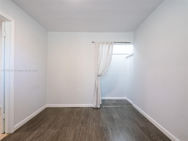 unfurnished room with dark wood-type flooring and baseboards