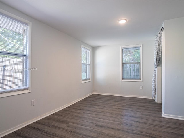 spare room featuring baseboards and dark wood finished floors