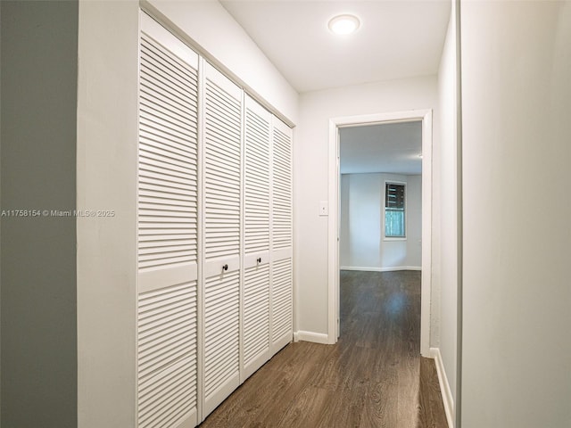 corridor with baseboards and dark wood-style flooring