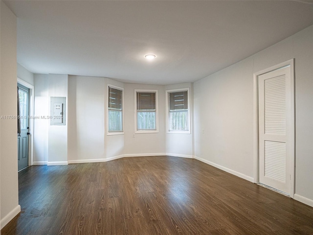 spare room with dark wood-style floors and baseboards