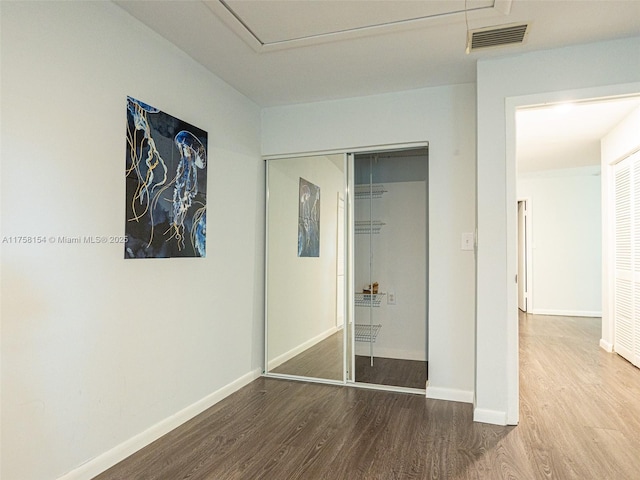 unfurnished bedroom with a closet, visible vents, baseboards, and wood finished floors