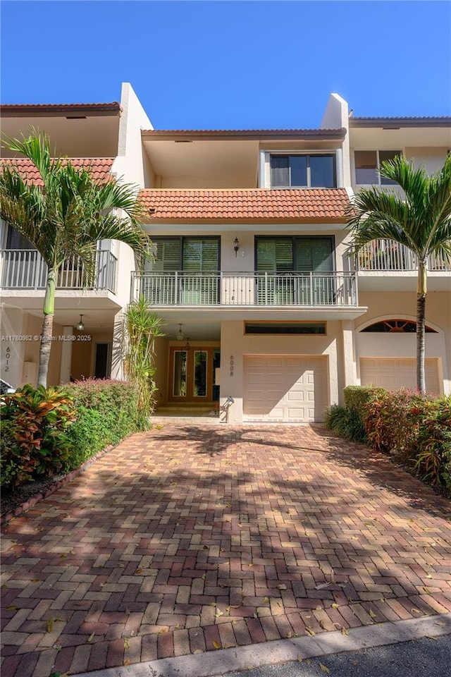 view of front facade featuring decorative driveway, a garage, a tile roof, and stucco siding