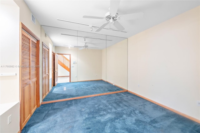 carpeted spare room featuring track lighting, a ceiling fan, visible vents, and baseboards