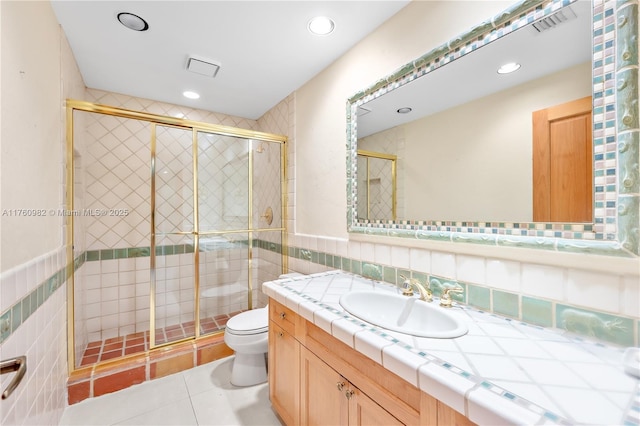 full bath with vanity, a shower stall, tile walls, toilet, and tile patterned floors