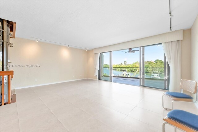 living area with rail lighting, baseboards, a ceiling fan, and a water view