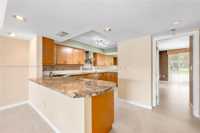 kitchen featuring visible vents, a sink, backsplash, wall chimney exhaust hood, and black electric stovetop