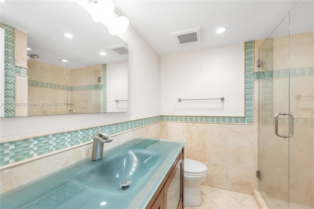 full bathroom with visible vents, toilet, vanity, a stall shower, and tile walls