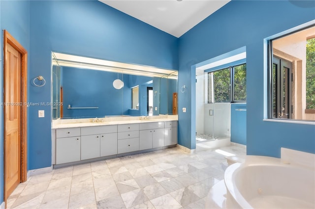 bathroom featuring a shower stall, a garden tub, double vanity, and a sink