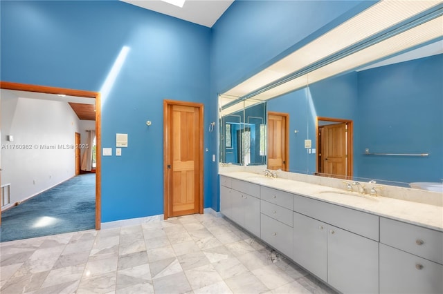 full bathroom featuring double vanity, a high ceiling, a skylight, and a sink