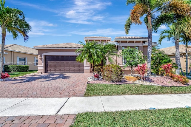 mediterranean / spanish-style home with decorative driveway, a garage, a tile roof, and stucco siding