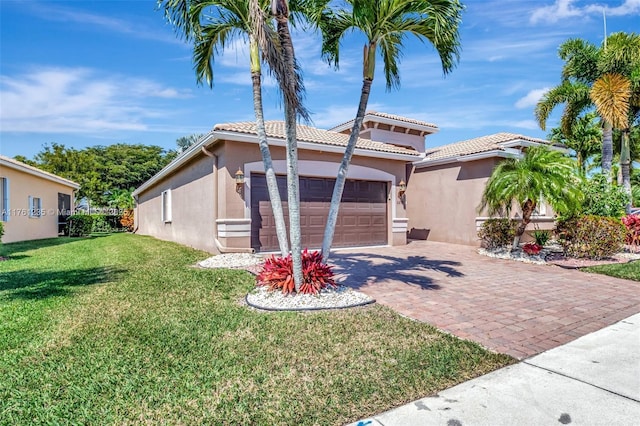 mediterranean / spanish home with stucco siding, decorative driveway, a front yard, an attached garage, and a tiled roof