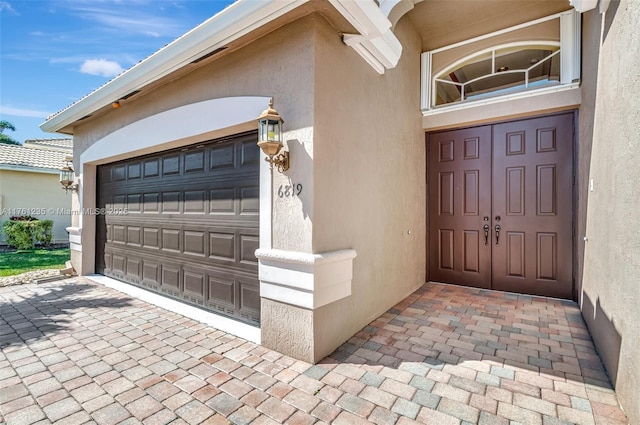 entrance to property with an attached garage and stucco siding