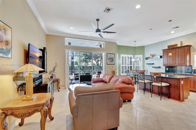 living area with visible vents, ceiling fan with notable chandelier, recessed lighting, crown molding, and light tile patterned floors