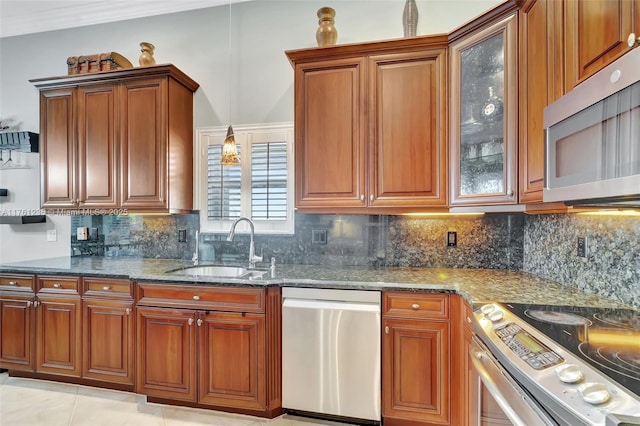 kitchen featuring a sink, stainless steel appliances, brown cabinetry, and dark stone countertops