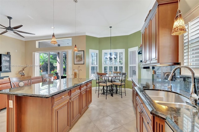 kitchen featuring dark stone countertops, brown cabinets, crown molding, and a sink