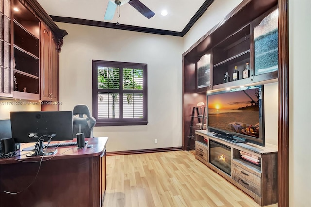 office space with crown molding, a ceiling fan, light wood-type flooring, and baseboards