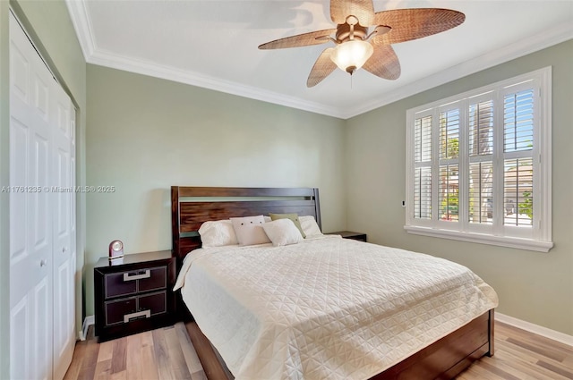 bedroom featuring crown molding, baseboards, ceiling fan, light wood-style flooring, and a closet