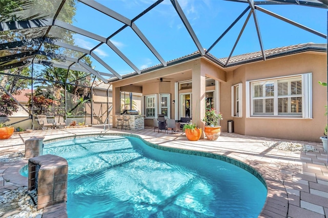 pool featuring ceiling fan, glass enclosure, a patio, and outdoor dry bar