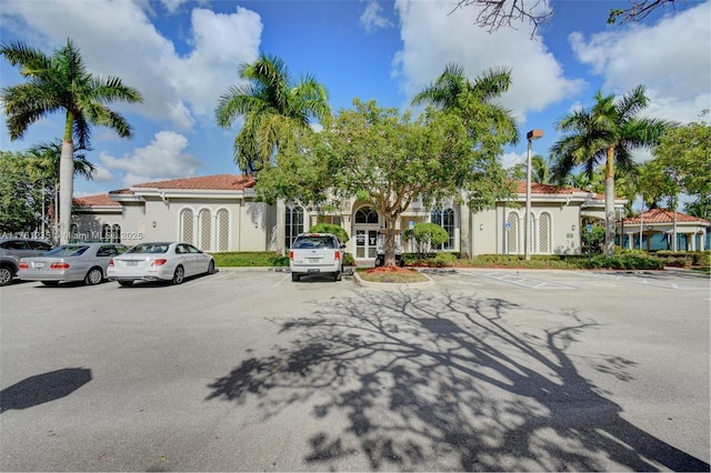 mediterranean / spanish-style house featuring a tiled roof, uncovered parking, and stucco siding