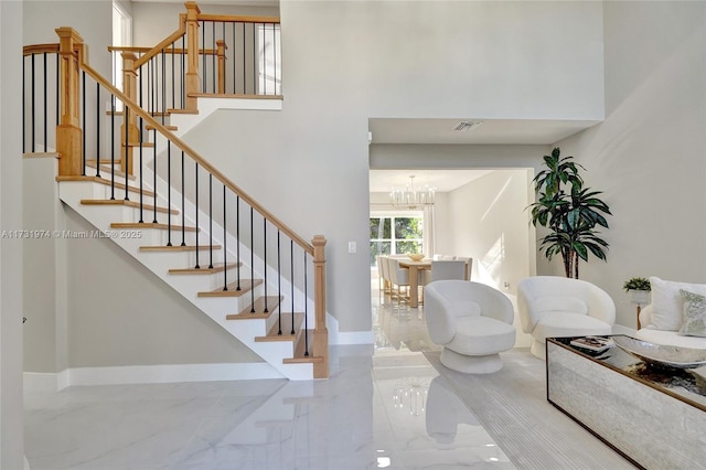 entryway featuring visible vents, marble finish floor, stairway, a high ceiling, and baseboards