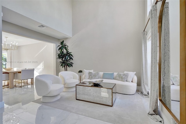 living area featuring a notable chandelier, visible vents, and a towering ceiling