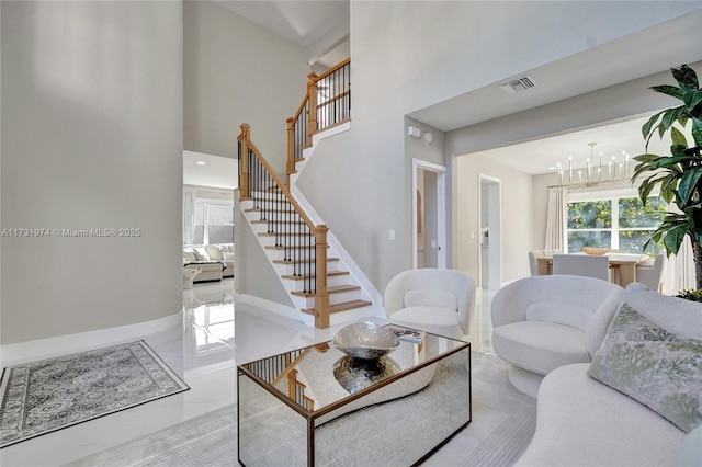 living area featuring stairway, visible vents, baseboards, a towering ceiling, and a chandelier