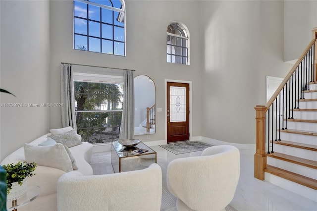 living room featuring baseboards, marble finish floor, a towering ceiling, and stairs