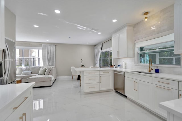 kitchen featuring marble finish floor, a sink, white cabinetry, stainless steel appliances, and a peninsula