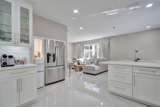 kitchen featuring stainless steel fridge with ice dispenser, light countertops, white cabinets, glass insert cabinets, and marble finish floor