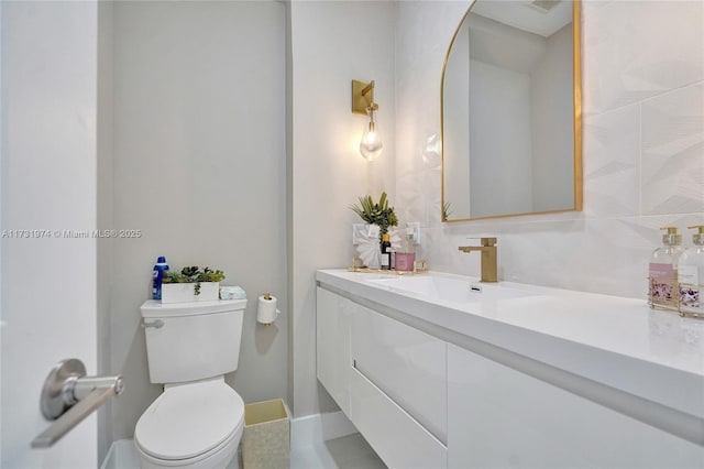 bathroom featuring vanity, toilet, and baseboards