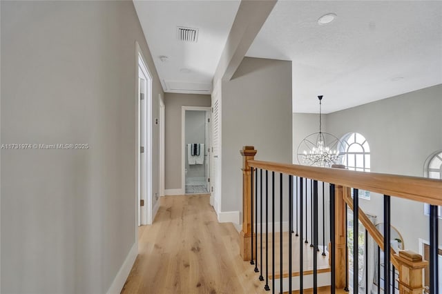 hall featuring a notable chandelier, visible vents, an upstairs landing, and baseboards