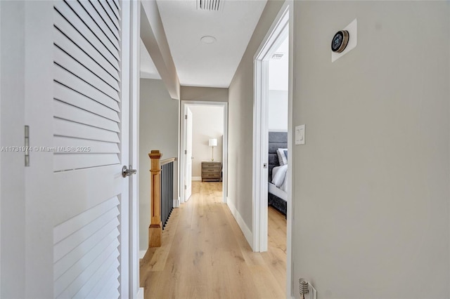 hall with visible vents, baseboards, and light wood-style floors