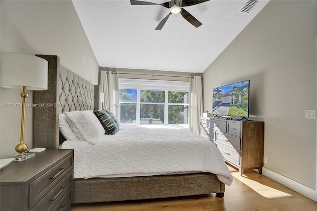 bedroom featuring visible vents, a ceiling fan, wood finished floors, baseboards, and vaulted ceiling