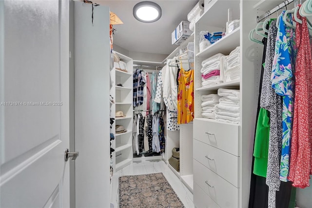 walk in closet featuring marble finish floor