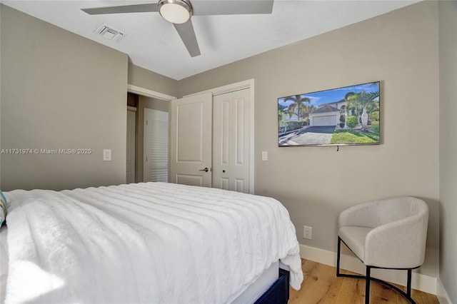 bedroom featuring a ceiling fan, visible vents, baseboards, light wood-style floors, and a closet