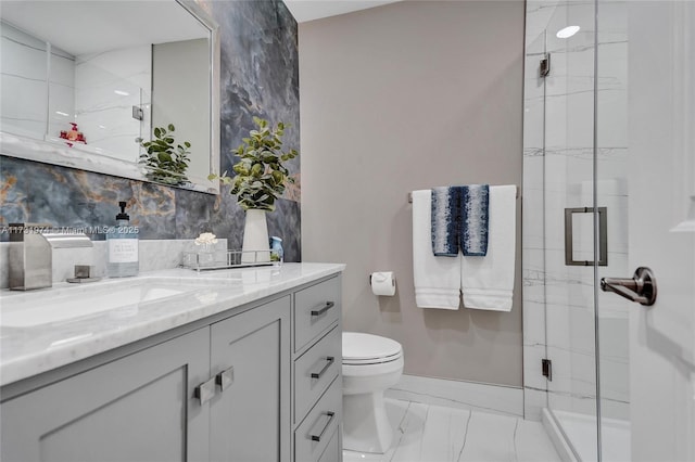 bathroom featuring toilet, marble finish floor, a stall shower, and vanity