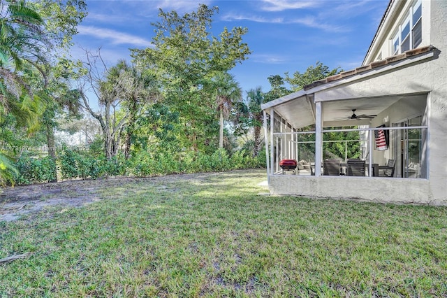 view of yard with a ceiling fan and a sunroom