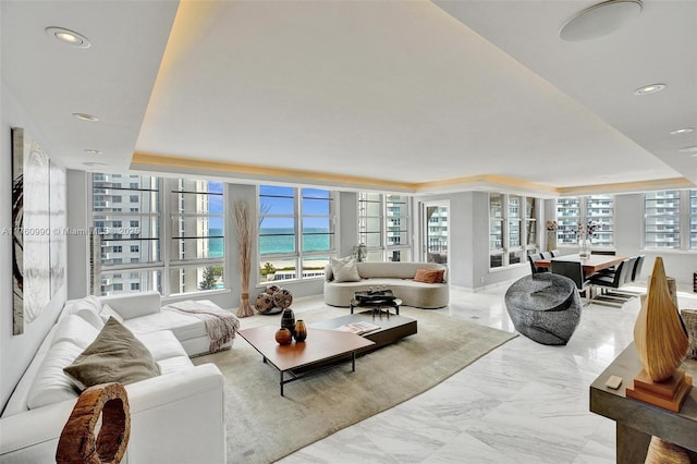 living room featuring recessed lighting, a raised ceiling, and marble finish floor