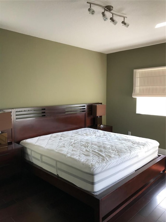 bedroom featuring rail lighting and wood finished floors