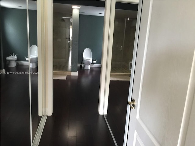 corridor featuring dark wood-type flooring and baseboards