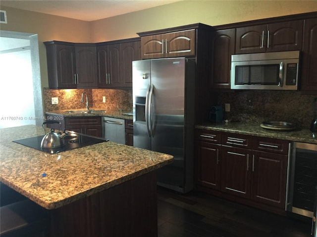 kitchen featuring tasteful backsplash, a sink, dark brown cabinets, appliances with stainless steel finishes, and dark wood-style flooring