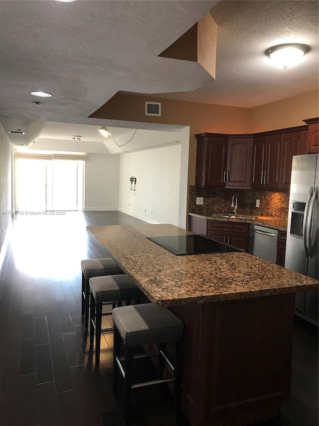 kitchen with dark wood-type flooring, tasteful backsplash, visible vents, and appliances with stainless steel finishes
