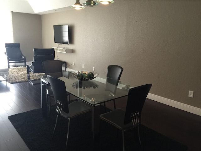 dining area featuring a textured wall, baseboards, and wood finished floors