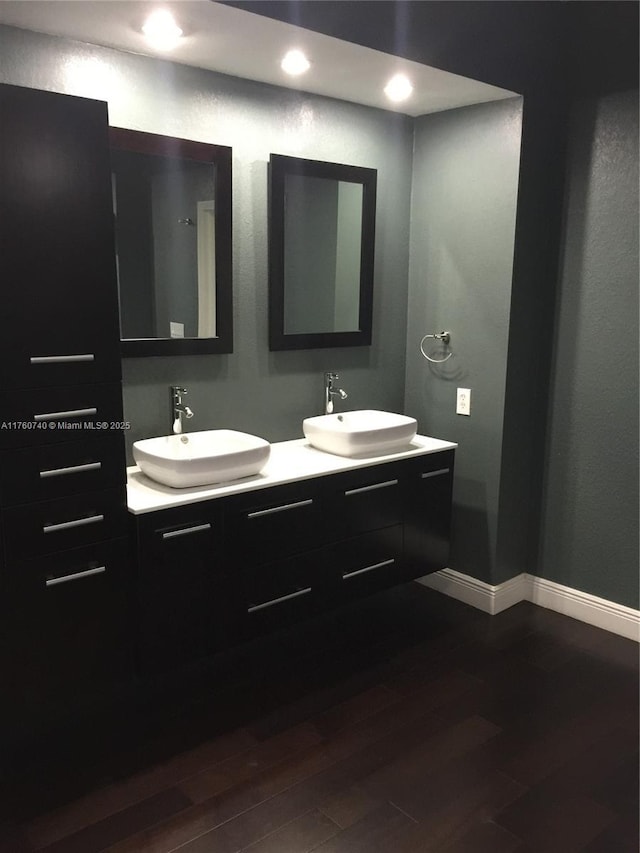 full bath featuring a sink, baseboards, and wood finished floors
