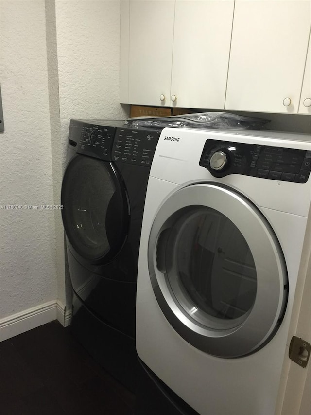 laundry area with washer and dryer, baseboards, cabinet space, and a textured wall